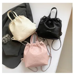 Close-up of three quilted drawstring bags in cream white, classic black, and light pink
