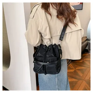 Model wearing a black nylon drawstring bucket bag with a light brown trench coat and jeans