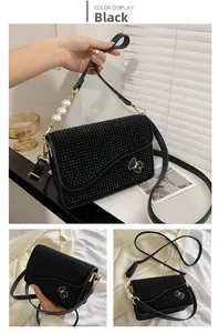 Close-up of black crossbody bag with shimmering rhinestones, pearl handle and bear charm