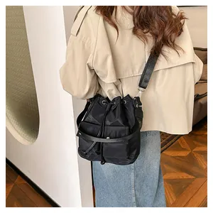 Detailed view of the drawstring closure and symmetrical flap pockets on the black bucket bag