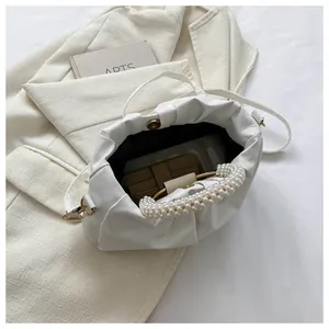 Detail der weißen Plissee-Handtasche mit doppeltem Perlengriff und geräumigem Innenfach