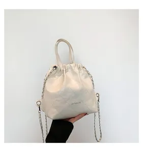Close-up of white quilted drawstring bucket bag with glossy finish and chain strap