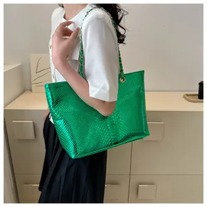 Detail of metallic green snake-embossed tote bag with golden chain and faux leather strap