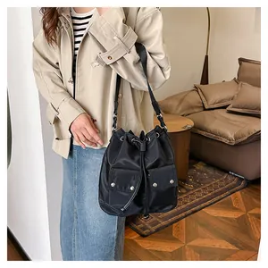 Detail of black drawstring bucket bag with dual front pockets and silver metal snaps