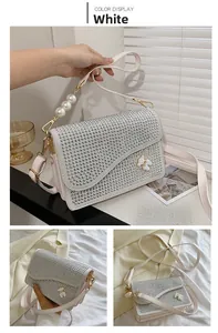 Detailed view of white crossbody bag with sparkling rhinestones and pearl handle