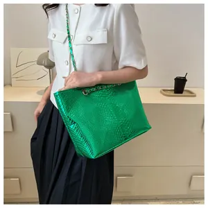 Detail of green snake-print tote bag with metallic texture and gold chain strap