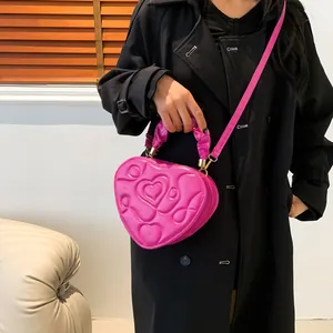 Modische rosarote herzförmige Handtasche mit Steppmuster für Damen, am Model gezeigt