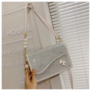 Detail of white square bag with silver studs, pearl accents and bow buckle decoration