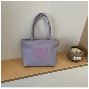 Detailed view of a purple nylon mini tote bag with a smiley heart patch on a wooden shelf