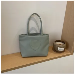 Detail showing the light blue nylon tote bag with a heart smiley face patch on a wooden shelf