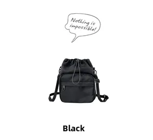 Close-up of black nylon bucket bag with drawstring closure and functional front zipper pocket
