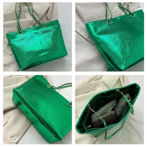 Detail view of large green snakeskin tote bag with chain strap and spacious interior