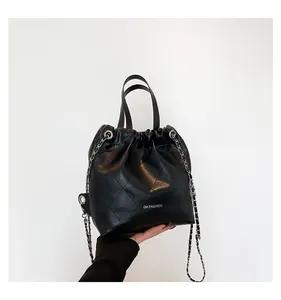 Detail of black quilted leather bucket bag with silver chain strap and drawstring closure
