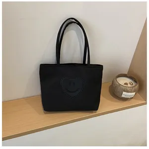 Detail of black nylon mini tote bag featuring a heart-shaped smiley face patch