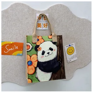 Detail of felt tote bag with hand-painted panda and floral illustration and beige handles