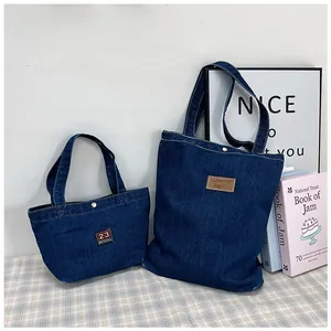 Detail of a two-piece set of large navy denim tote bags with vintage embroidery patches