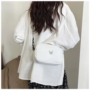 Détail d'un sac bandoulière en nylon blanc avec une large sangle à imprimé lettres