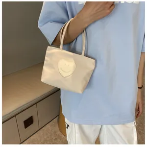 Close-up of heart patch with smile face on cream nylon mini handbag with double handles