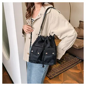 Detail shot of black nylon bucket bag featuring drawstring closure and silver rivet pockets