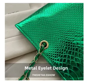 Detail of green faux crocodile leather texture and golden metal chain eyelet on handbag