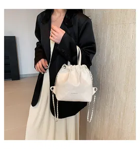 Detail showing creamy white quilted bucket bag with gold chain strap and drawstring closure