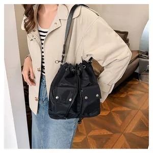 Detail of black nylon drawstring bucket bag with cargo pockets and adjustable shoulder strap