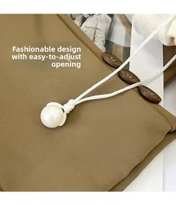 Detail of white pearl pendant with adjustable braided cord on brown fabric background