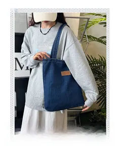 Detail of dark blue denim tote bag with leather Cowboy bag tag and fabric texture