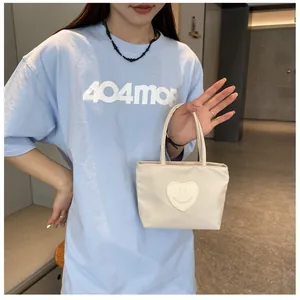Detail of cream mini nylon handbag featuring a cute heart-shaped smiley face patch