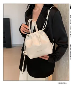 Detail of white quilted drawstring bag with chain strap and brand logo on soft leather
