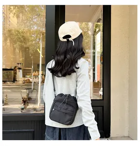 Detailed view of lightweight black nylon bucket bag with drawstring and front zip pocket