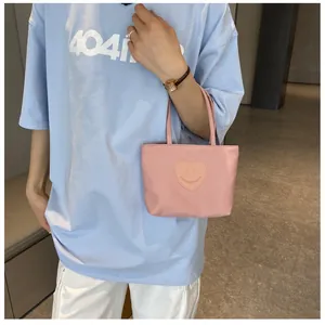 Detailed close-up of a pink nylon mini handbag featuring a cute heart patch on a model arm