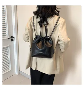 Rear view of model wearing a black quilted leather bucket bag with silver chain straps