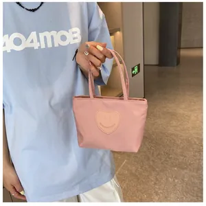 Detail of light pink nylon mini tote bag with a heart-shaped smiley face patch