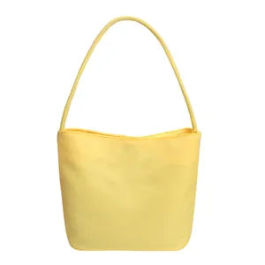 Detailansicht einer gelben Nylon-Schultertasche mit schmalem Gurt und Trapezform