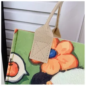Detail view of reinforced stitching on handles of the green felt tote bag with floral print