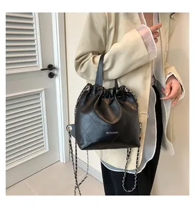 Detail of black quilted bucket bag with silver chain strap and drawstring closure