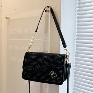 Black rhinestone crossbody bag with gold bear logo and large white pearl strap accent
