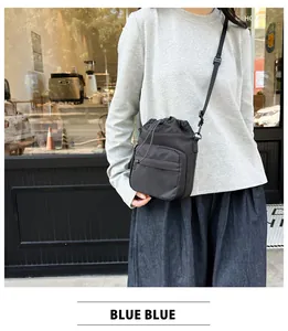 Detail view of black nylon drawstring bucket bag with adjustable strap worn by model