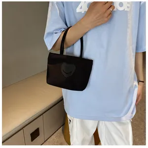 Detail of a mini black nylon tote bag with heart smile patch held by a model