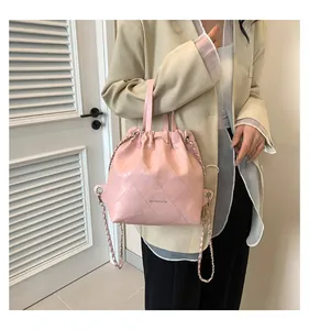Close-up of pink quilted bucket bag showing chain strap on model with shutter background