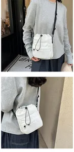 Detailed view of a white nylon drawstring bucket bag with adjustable shoulder straps