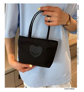 Detailed shot of a black mini nylon tote bag with a cute heart smiley face patch