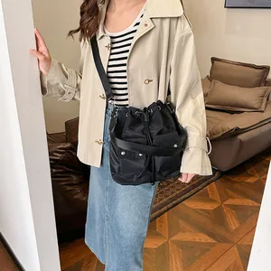 Minimalist black nylon bucket bag with adjustable shoulder strap and snap front pockets