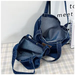Detail of dark blue denim tote bags with magnetic closure and vintage leather patch