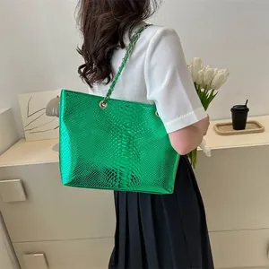 Metallic green tote bag with snakeskin texture and gold chain strap shown on shoulder