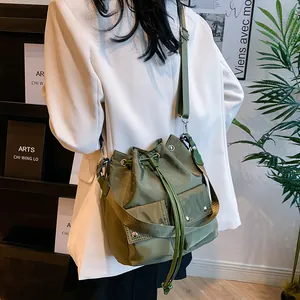 Army green nylon bucket bag with cargo pockets and adjustable shoulder strap worn by model