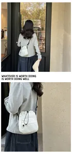 Detailed view of white nylon drawstring bucket bag featuring a black adjustable shoulder strap