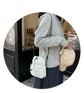 Close-up of a white nylon bucket bag with drawstring closure and front zipper pocket