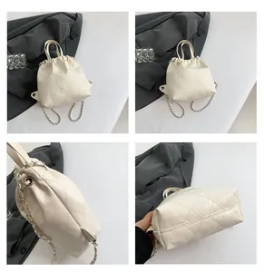 Macro view of cream white quilted bucket bag featuring a chain strap and drawstring detail